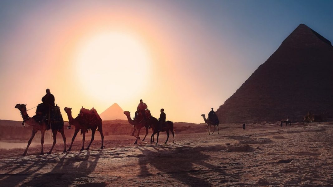 men-and-camels-next-to-egyptian-pyramids-sunset